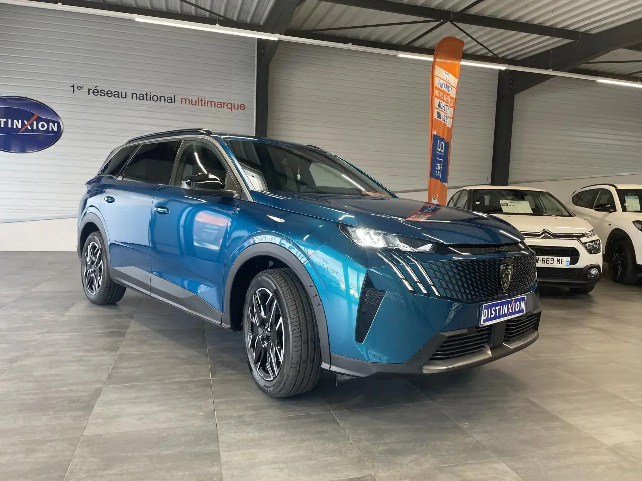 Peugeot 5008 bleu Obsession vue 3/4 avant droit en showroom avec jantes alliage noires diamantées.