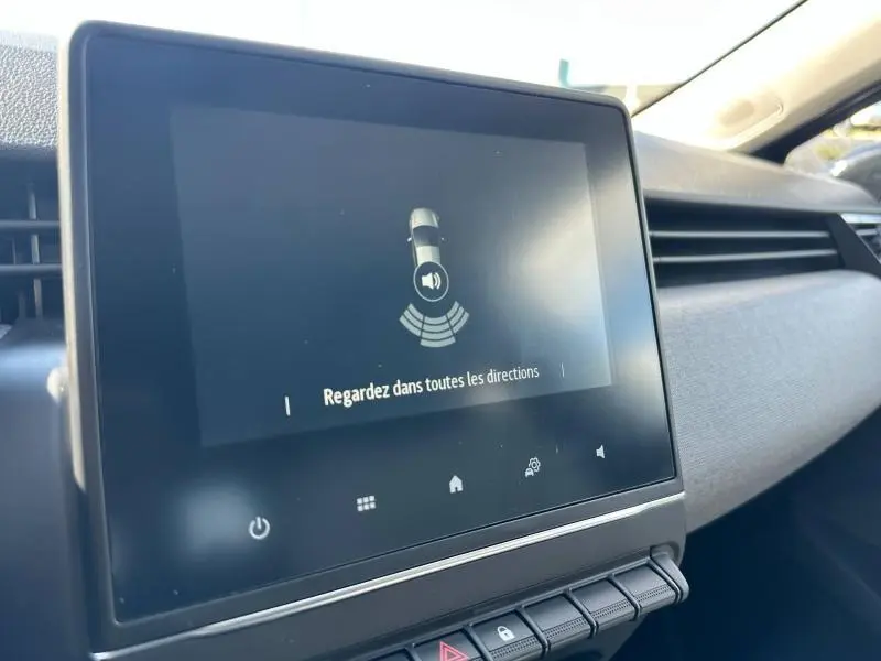 Écran tactile central de la Renault Clio 2025 affichant une alerte de détection d'obstacles, intérieur gris.