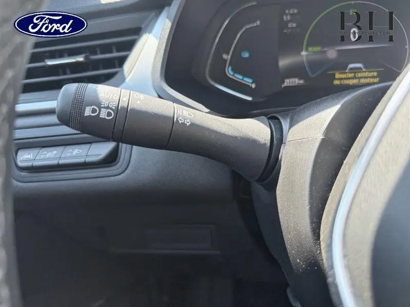 Gros plan sur la commande des phares et clignotants à gauche du volant dans un intérieur sombre.