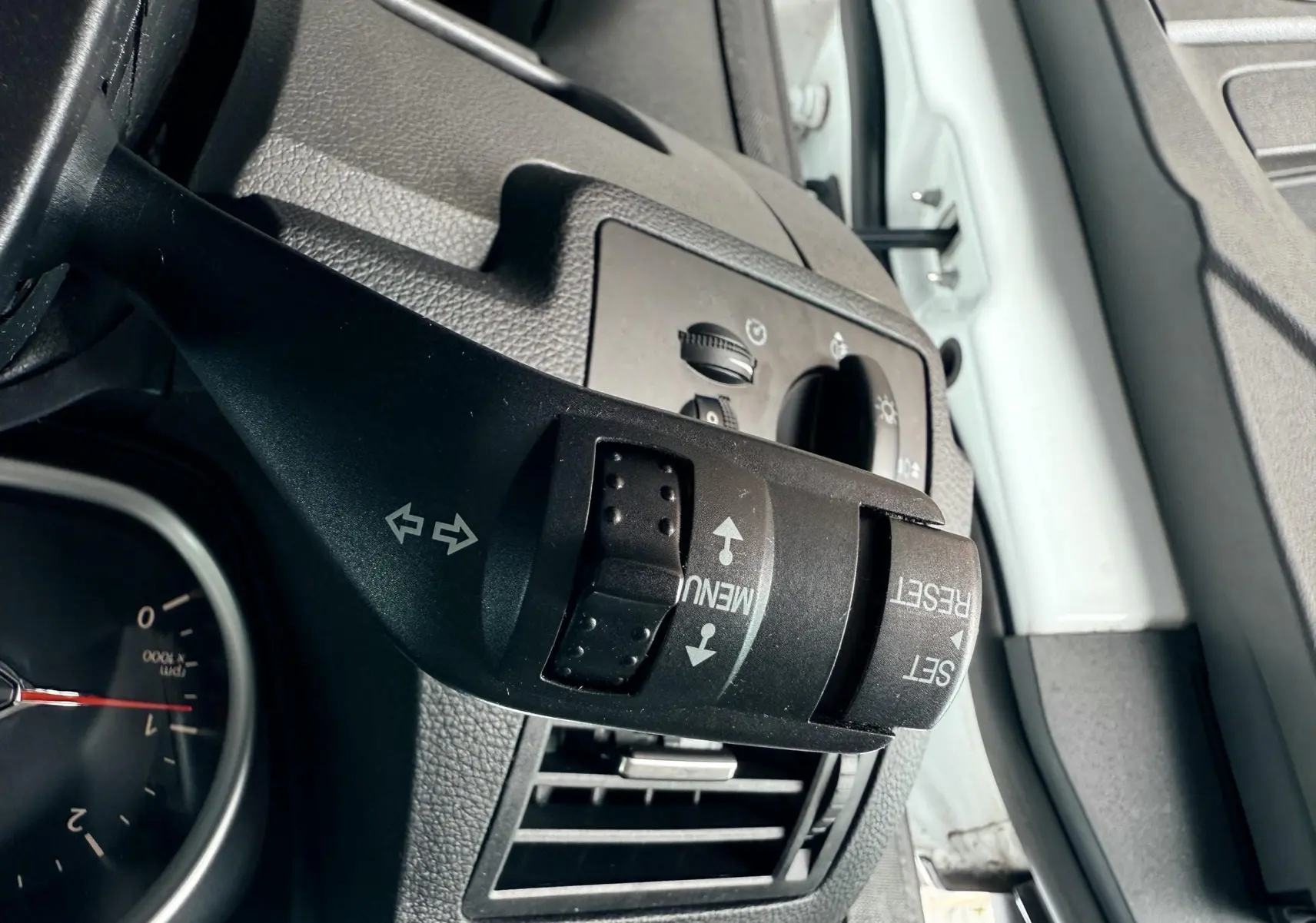 Gros plan sur la commande de clignotants et menu du tableau de bord du Ford Kuga blanc, côté gauche intérieur.