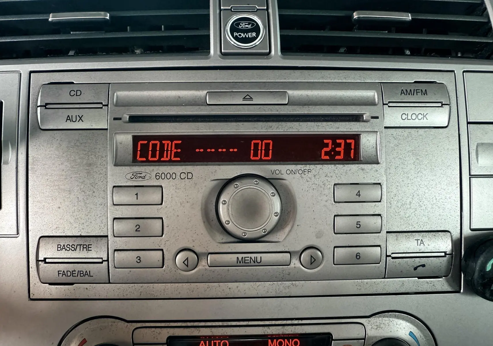 Gros plan sur la console centrale du Ford Kuga blanc de 2012, affichant l'autoradio 6000 CD et la climatisation digitale.
