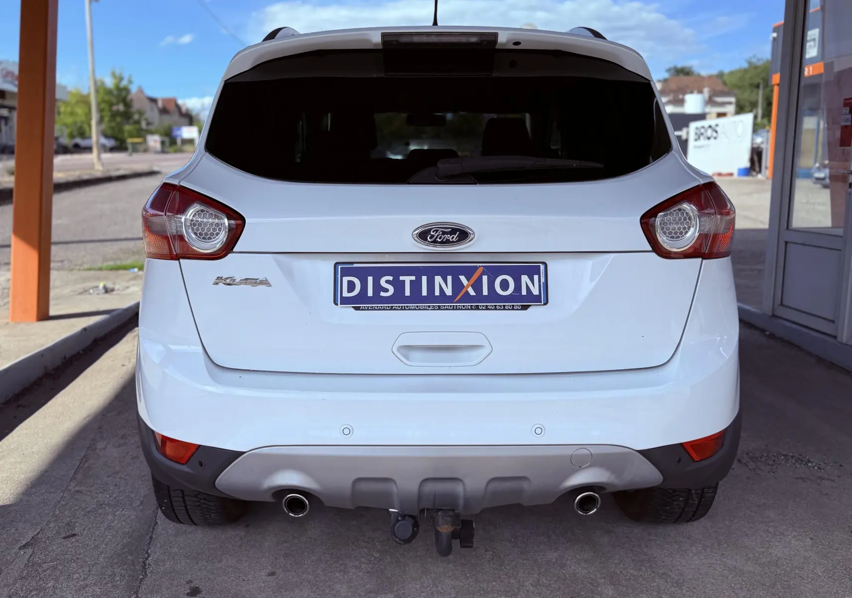 Vue arrière d'un Ford Kuga blanc de 2012 avec double sortie d'échappement et attelage visible.