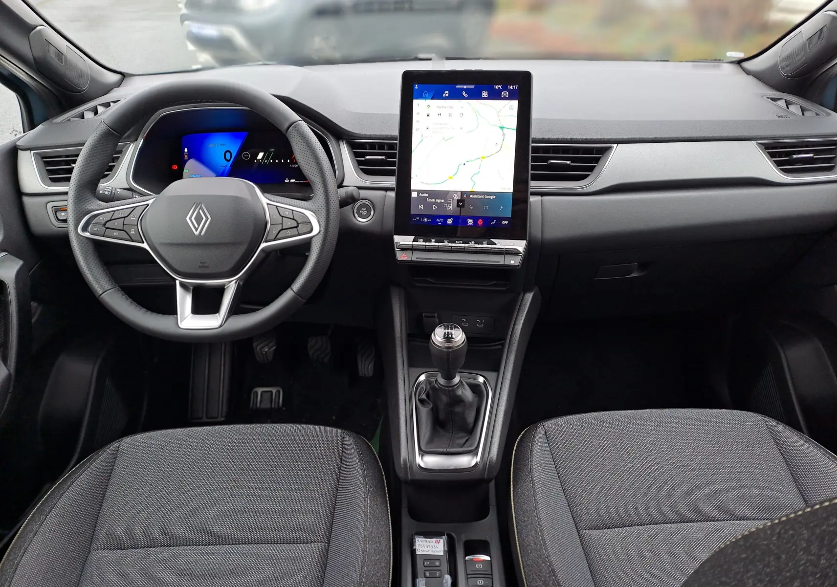 Vue intérieure avant du tableau de bord noir du Renault Symbioz avec volant multifonction et écran tactile vertical.