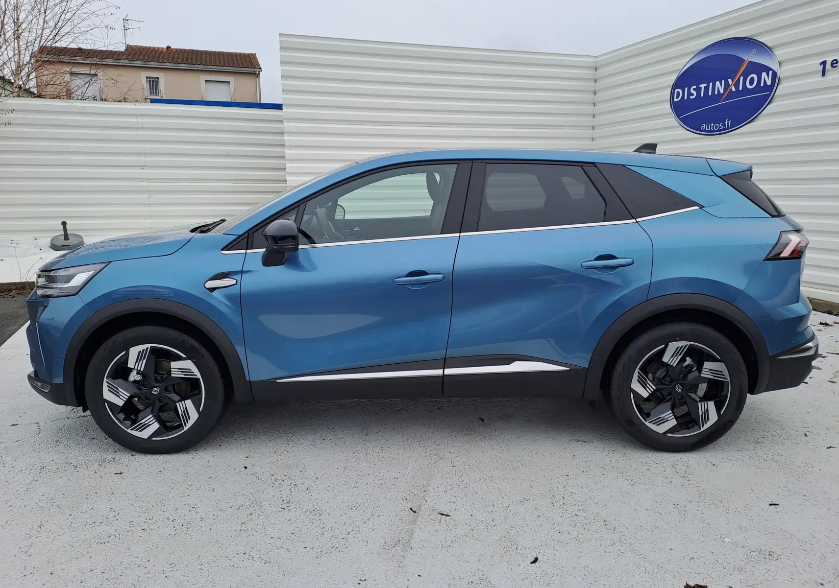 Profil latéral droit d’un Renault Symbioz bleu mercure 2025 avec jantes bicolores et détails chromés sur les portes.