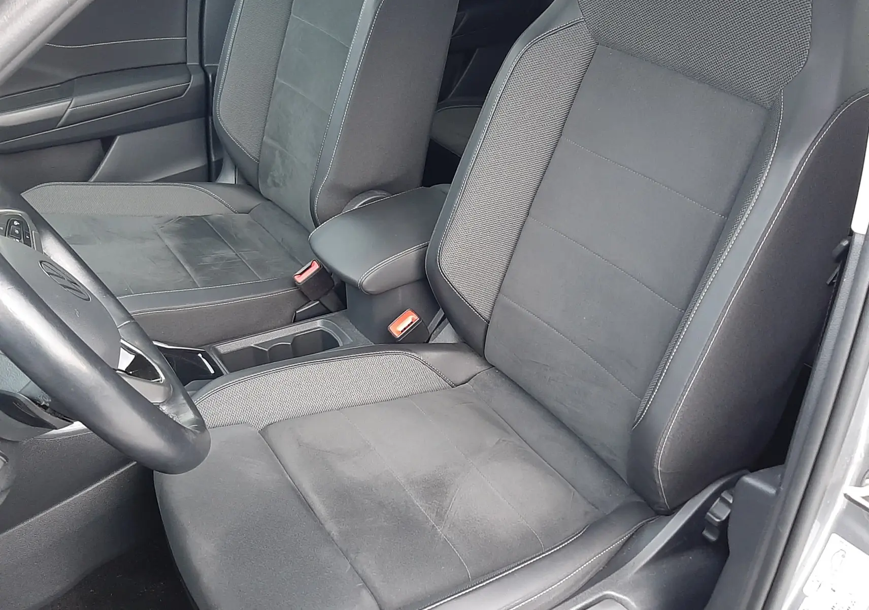 Vue intérieure côté conducteur du Volkswagen T-Roc gris pyrite 2023 avec sièges noirs en tissu et alcantara.