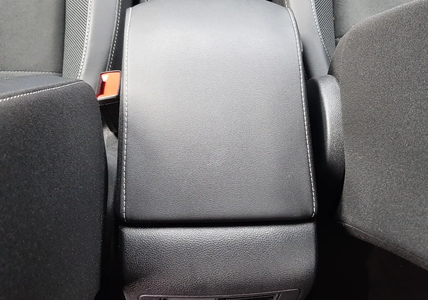 Vue plongeante sur l'accoudoir central noir et les sièges avant du Volkswagen T-Roc gris Pyrite 2023.