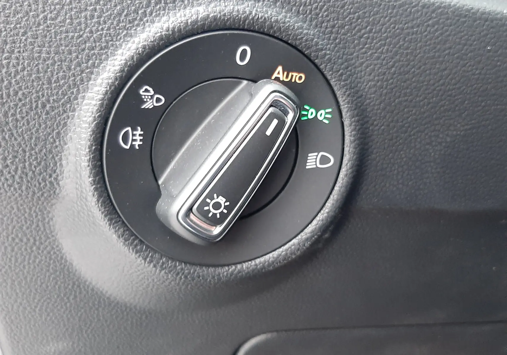 Sélecteur rotatif des phares en mode automatique sur tableau de bord noir d'un Volkswagen T-Roc 2023 gris pyrite