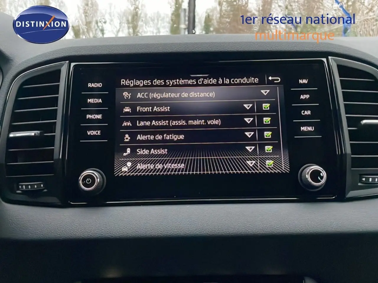 Écran central tactile du Skoda Karoq 2025 affichant les réglages des aides à la conduite, intérieur noir.