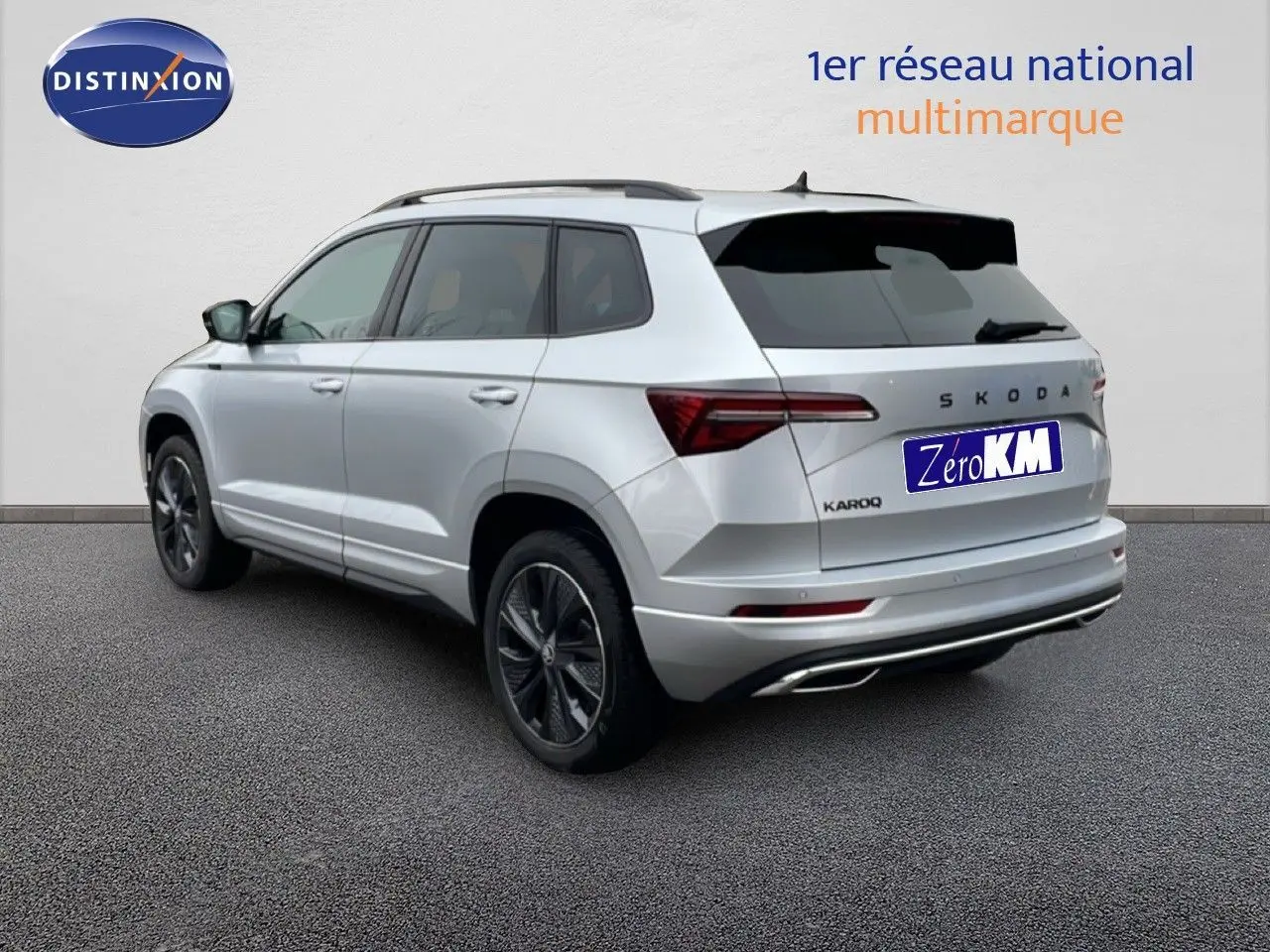 Vue 3/4 arrière droite d'un Skoda Karoq gris argent métallisé avec jantes noires et toit noir.