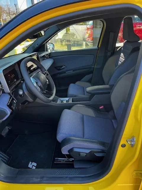 Vue intérieure côté conducteur de la Renault R5 Techno jaune 2024, avec sièges tissu gris et tableau de bord digital.