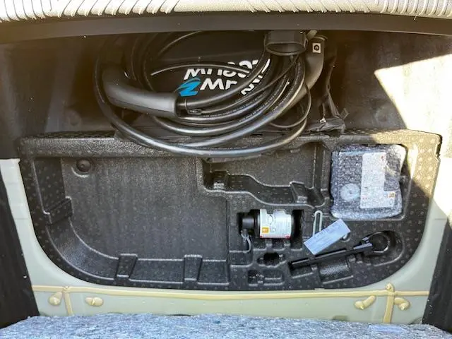 Vue rapprochée du coffre avant ouvert de la Renault R5 Techno jaune 2024, montrant le câble de charge et les outils de bord.