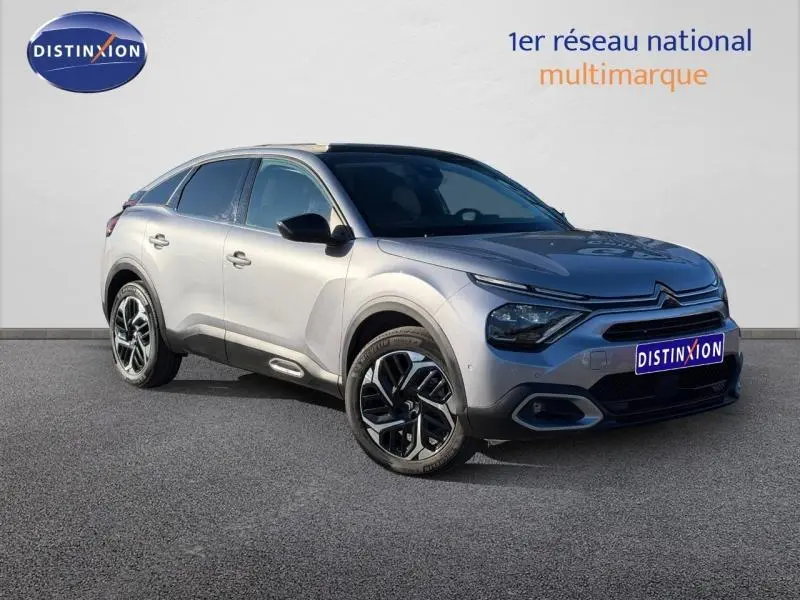 Vue 3/4 avant droite d'une Citroën C4 2024 gris acier avec jantes alliage et signature lumineuse distinctive.