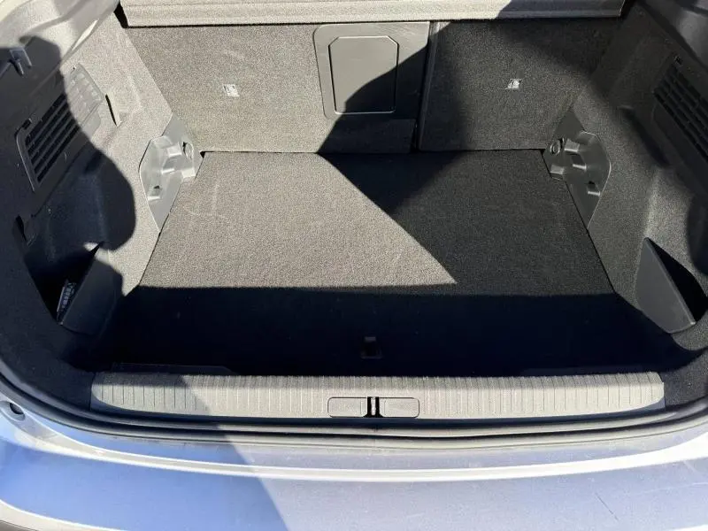 Coffre ouvert vu de l'arrière d'une Citroën C4 2024 gris acier, montrant un espace de chargement propre et spacieux.
