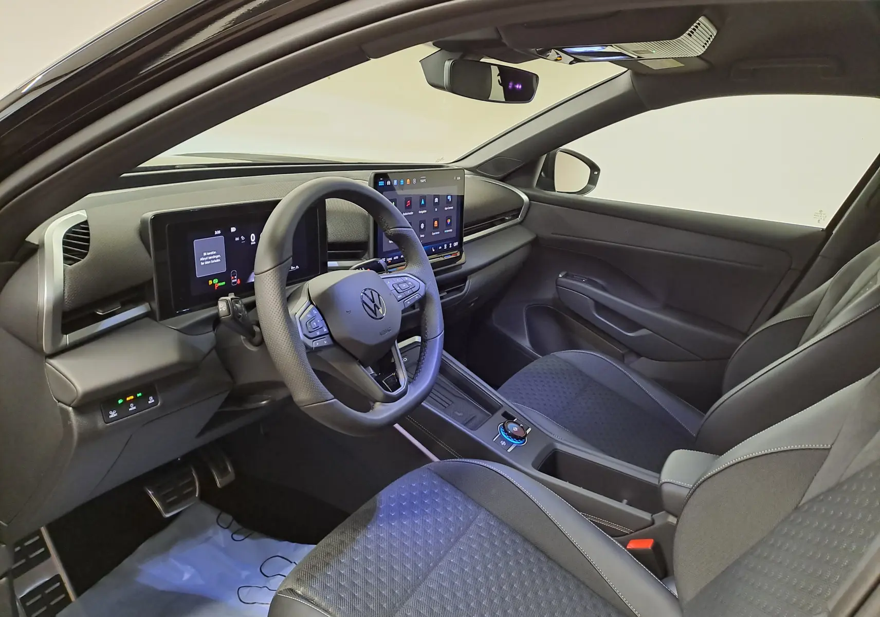 Vue intérieure côté conducteur du Volkswagen T-Roc 2026, tableau de bord numérique et sièges noirs en tissu et cuir.