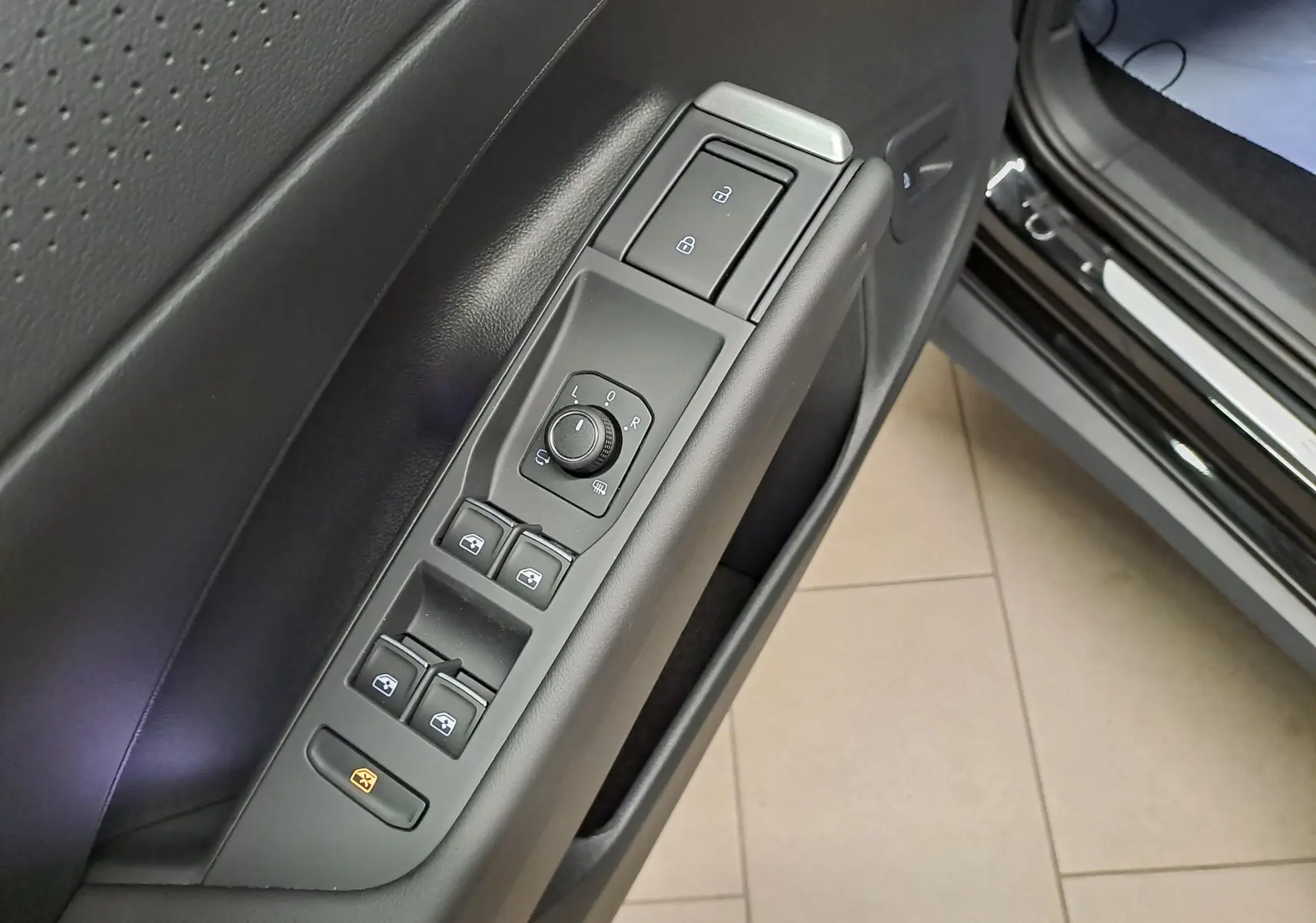 Gros plan sur la commande des vitres et rétroviseurs côté conducteur du Volkswagen T-Roc noir ébène 2026 R-Line.