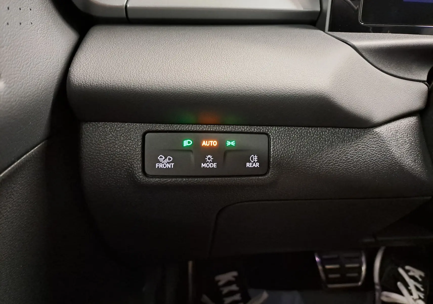 Détail du tableau de bord noir du Volkswagen T-Roc 2026 avec commandes d’éclairage automatiques et voyants allumés.