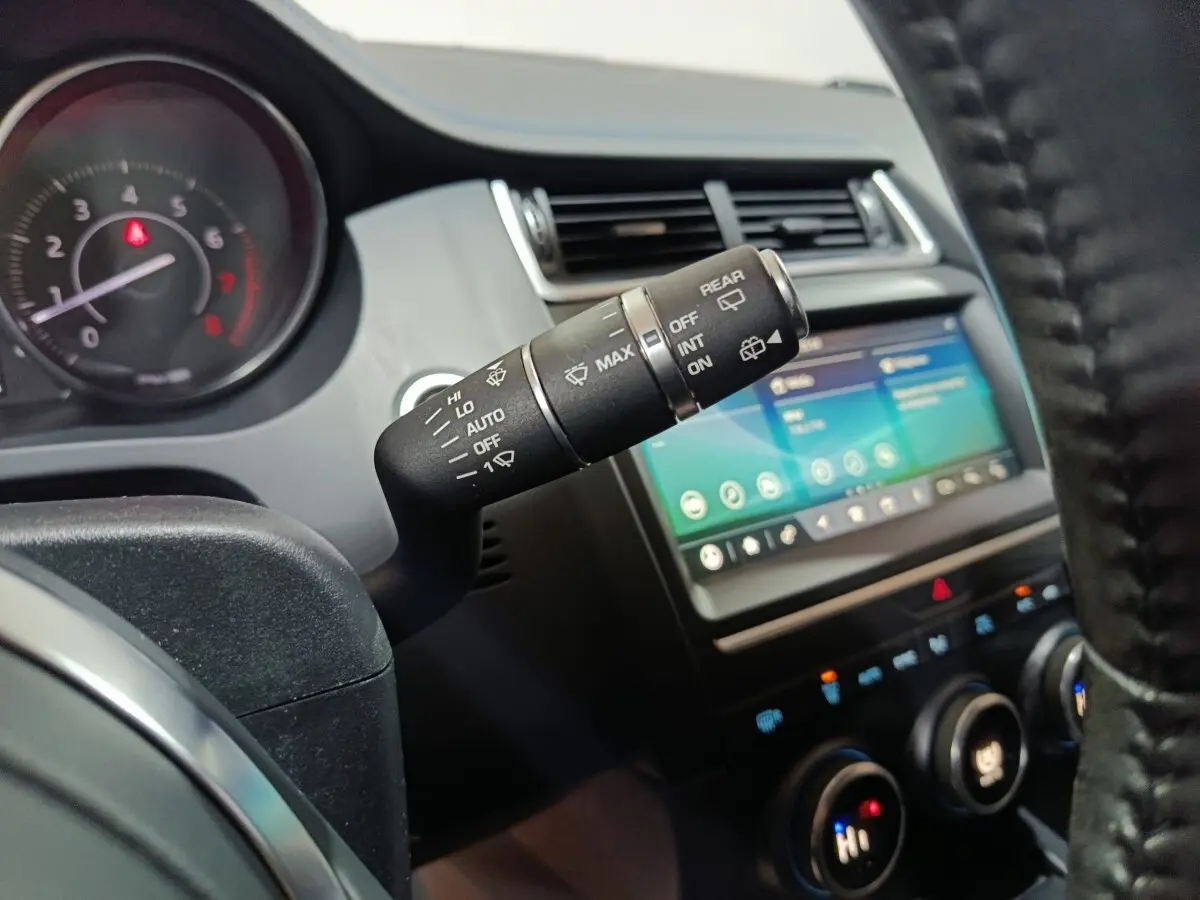 Gros plan sur la commande d’essuie-glace côté gauche du tableau de bord du Jaguar E-PACE noir, avec écran tactile visible.