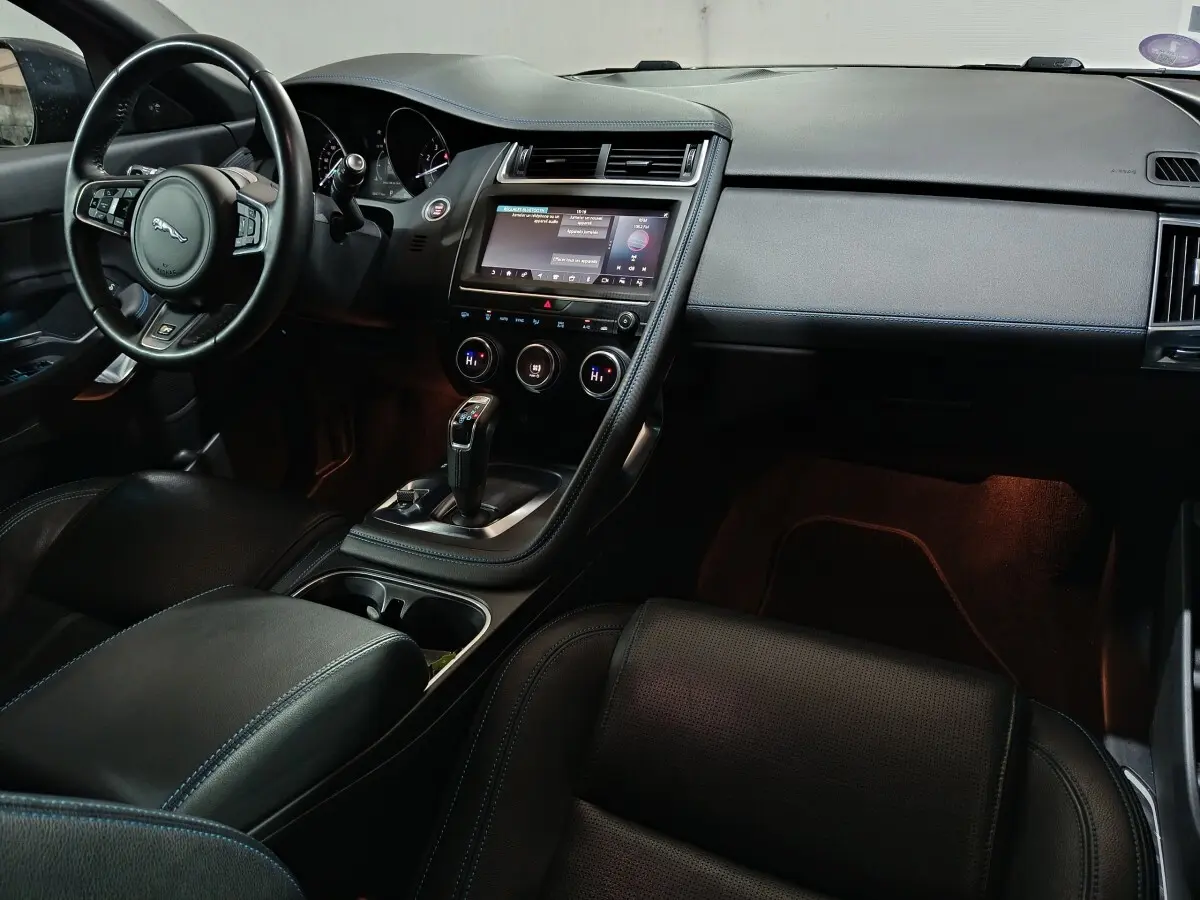 Intérieur noir de la Jaguar E-PACE 2019, vue côté conducteur, avec tableau de bord et écran tactile central lumineux.