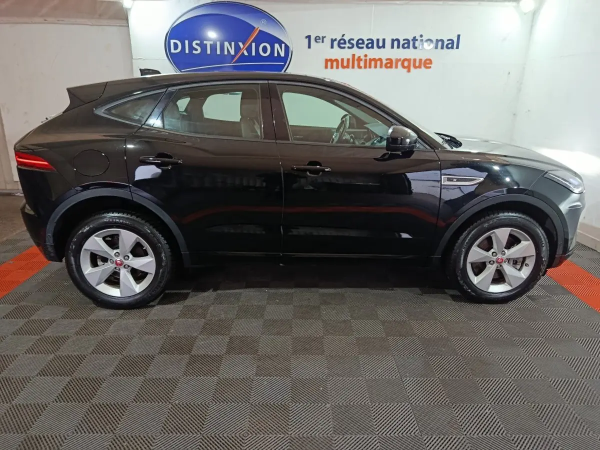 Vue de profil côté gauche d'un Jaguar E-PACE noir 2019 garé en intérieur avec jantes argentées et logo Jaguar visible.