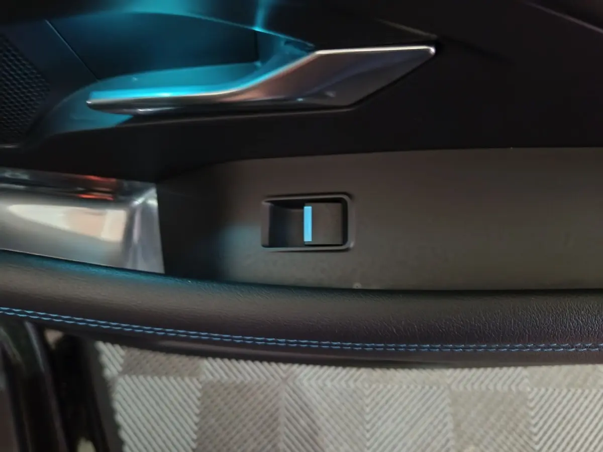 Détail de la poignée intérieure côté gauche avec couture bleue sur le cuir dans un Jaguar E-PACE noir.