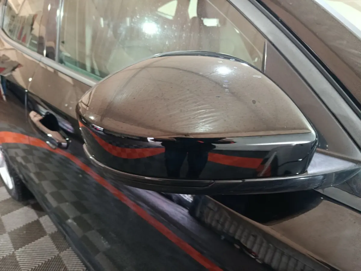 Rétroviseur côté gauche noir brillant du Jaguar E-PACE 2019 avec carrosserie noire en arrière-plan.