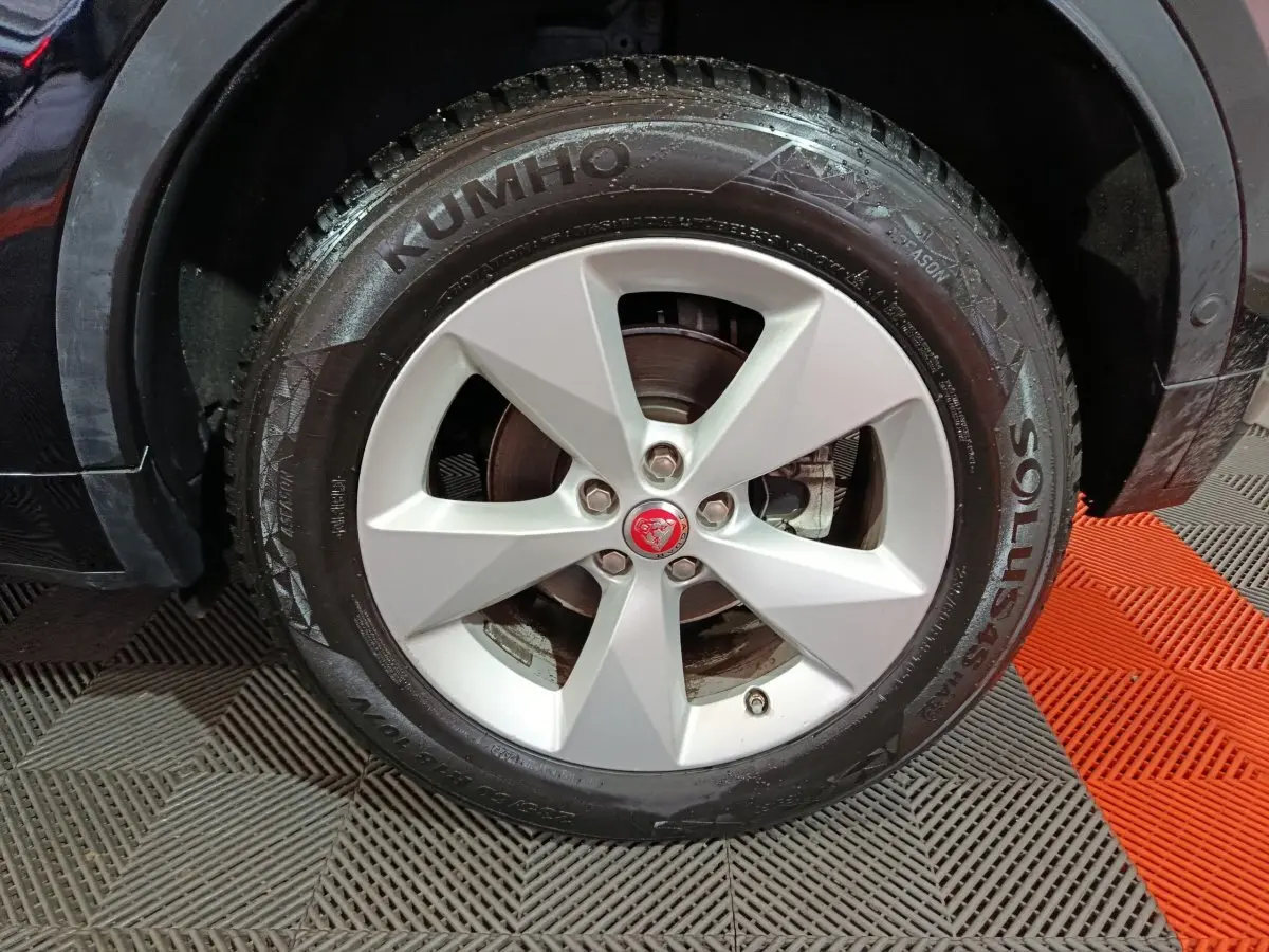 Gros plan sur la roue avant droite noire du Jaguar E-PACE 2019 avec jante argentée et logo Jaguar central rouge.