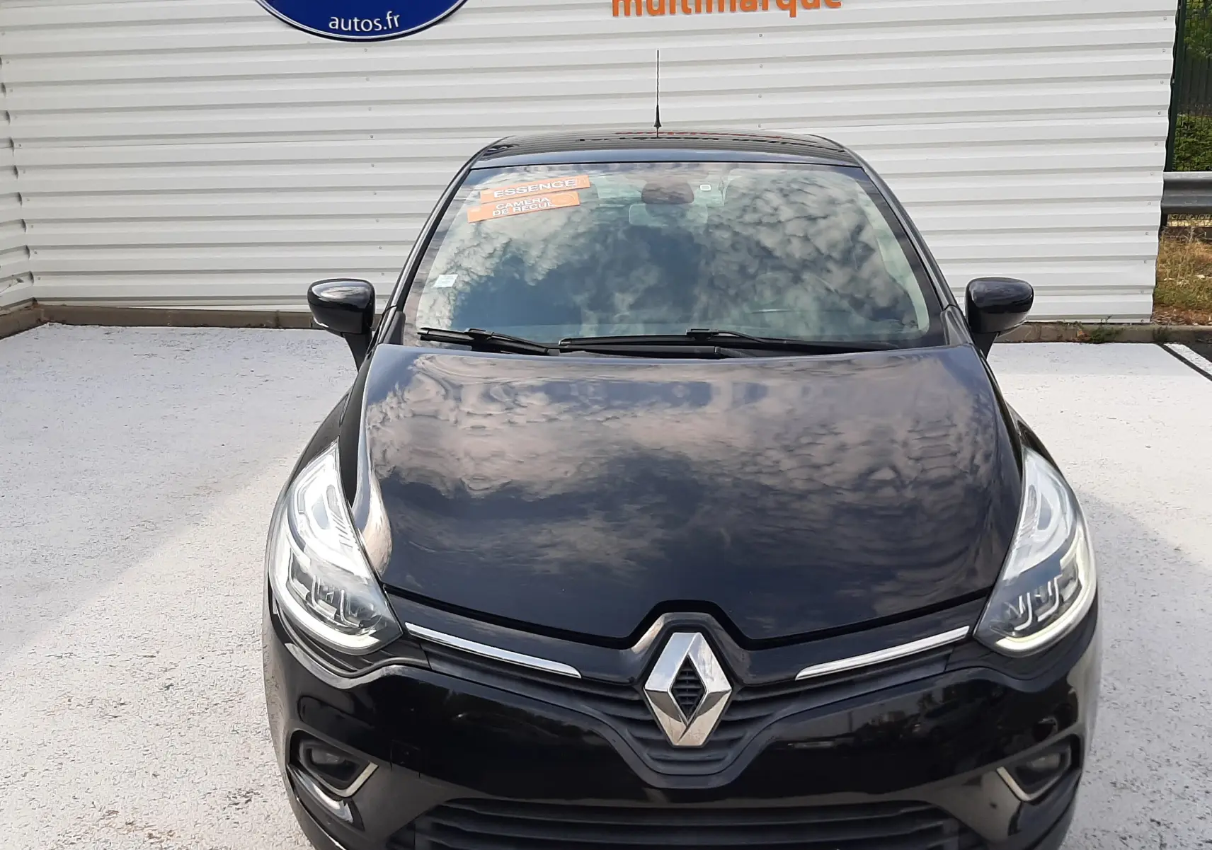 Vue avant d'une Renault Clio IV noire 2018 avec phares allumés et plaque "OCCASION" visible au sol.