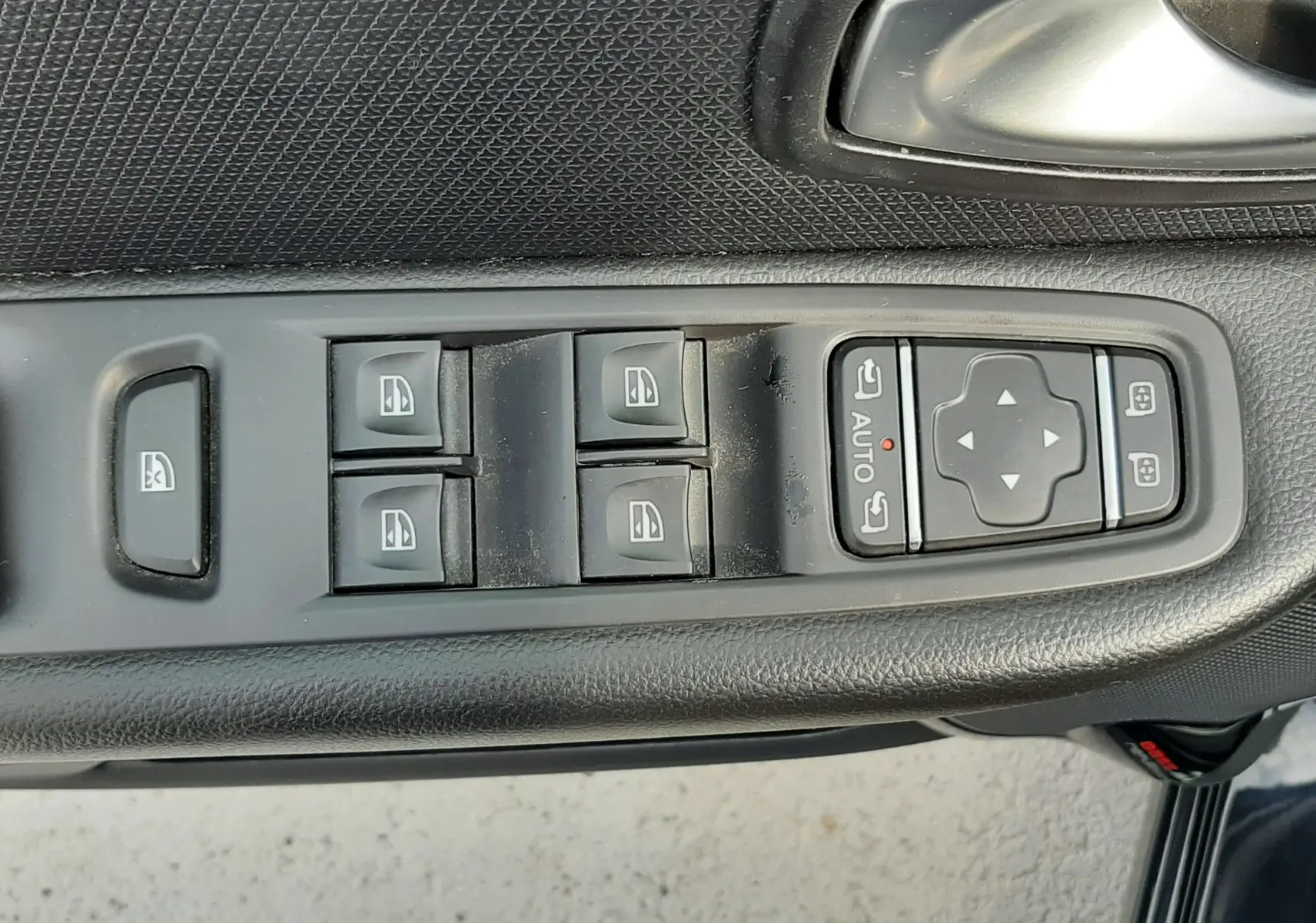 Vue rapprochée des commandes de lève-vitres et réglages des rétroviseurs sur la porte côté conducteur d'une Renault Clio IV noire.