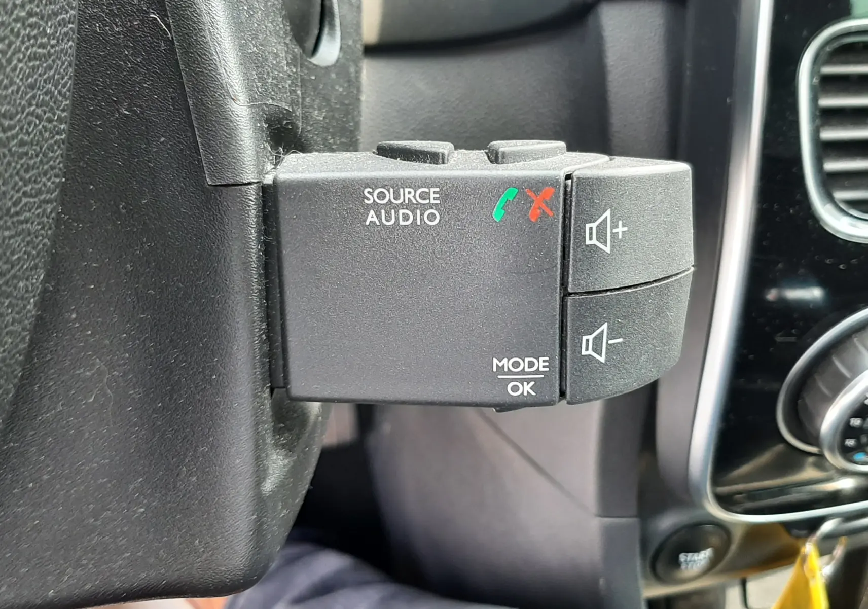 Gros plan sur la commande audio au volant côté gauche d'une Renault Clio IV noire, avec boutons de volume et appels.