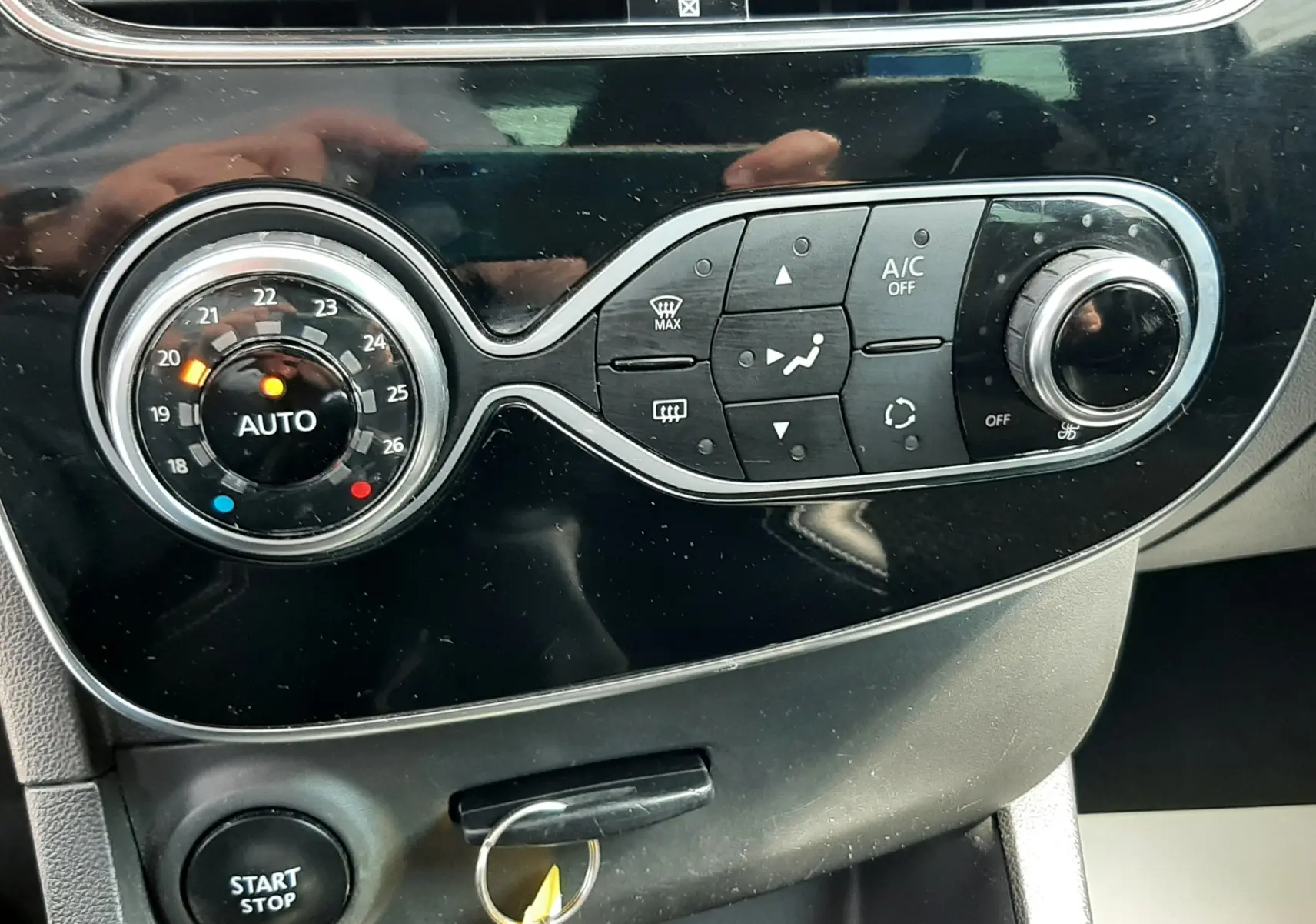 Vue rapprochée du tableau de bord noir de la Renault Clio IV 2018, mettant en valeur la commande de climatisation et le bouton start/stop.