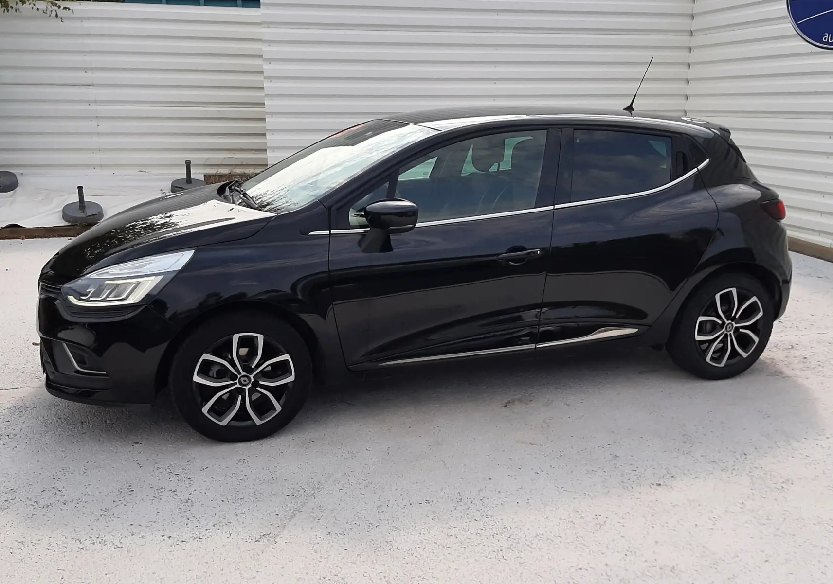 Profil côté gauche d'une Renault Clio IV noire 2018, avec jantes alliage bicolores et lignes fluides modernes.