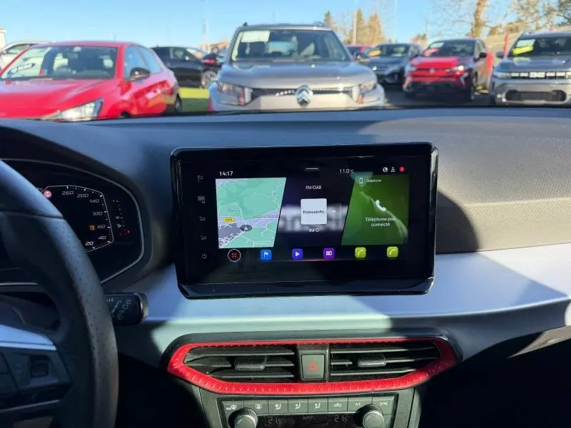 Vue intérieure du tableau de bord de la SEAT Ibiza 1.0 TSI FR 2025 avec écran tactile et cadre d'aération rouge.