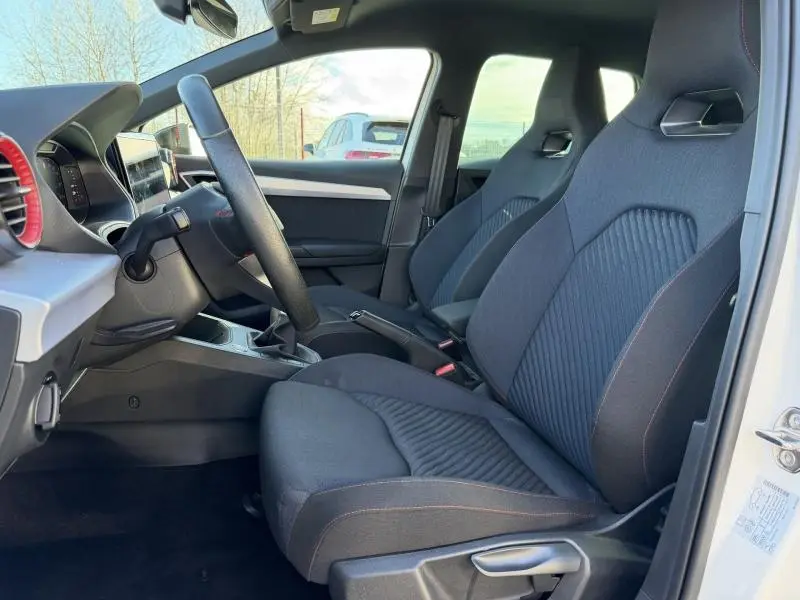Vue intérieure côté conducteur de la SEAT Ibiza 1.0 TSI FR 2025 avec sièges sport en tissu noir et volant multifonction.