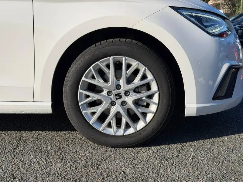 Gros plan sur la roue avant gauche de la SEAT Ibiza 1.0 TSI 115cv FR blanche Nevada métal avec jante alliage distinctive.