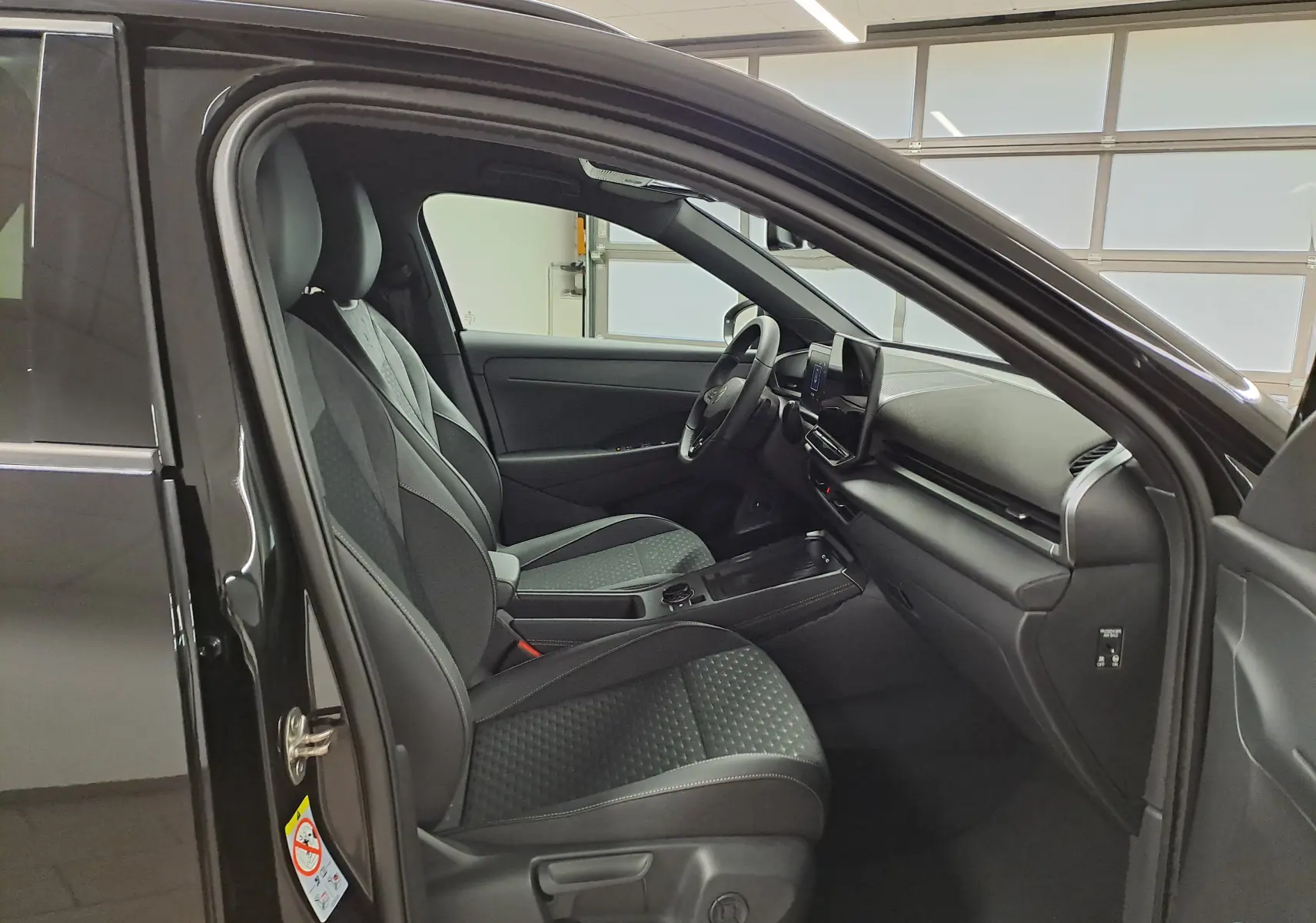 Vue intérieure côté conducteur du Volkswagen T-Roc 2026 noir ébène, sièges et tableau de bord modernes en tissu et cuir.