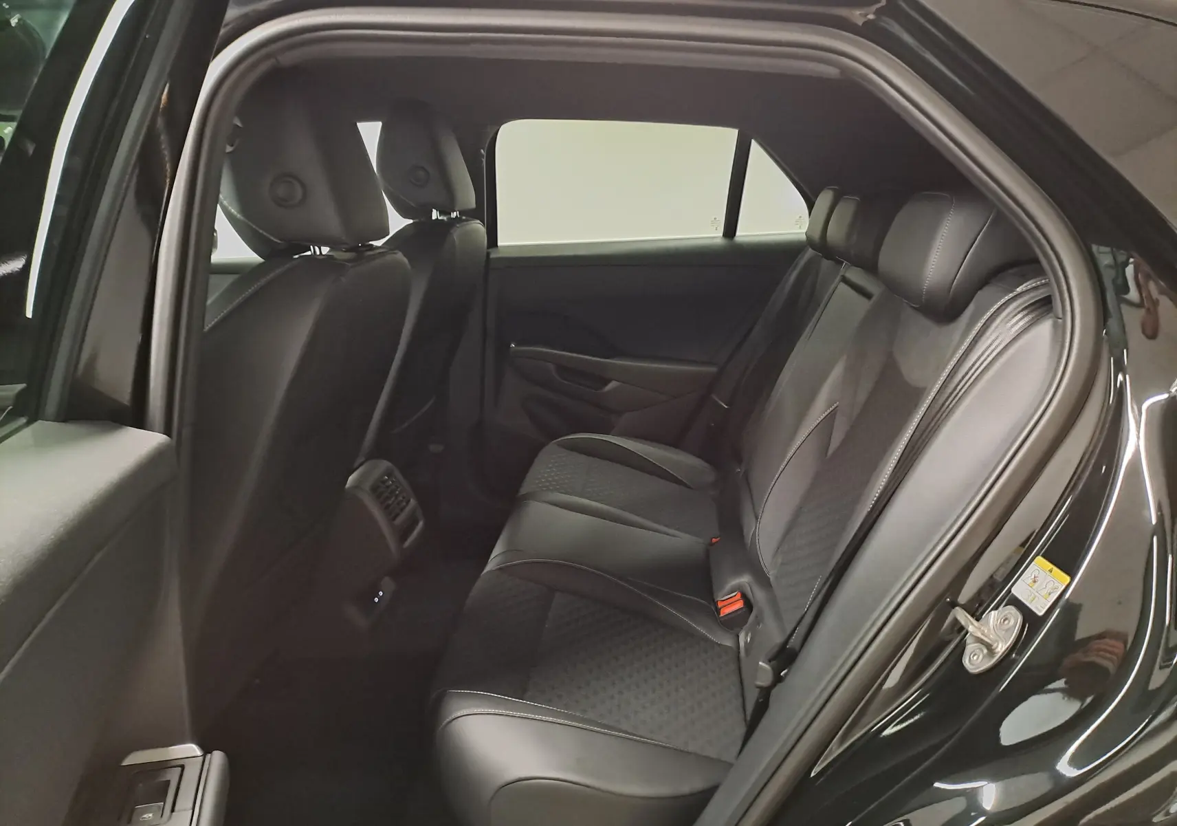 Vue intérieure côté droit des sièges arrière en cuir noir du Volkswagen T-Roc 2026 Noir Ébène, avec détails couture visibles.