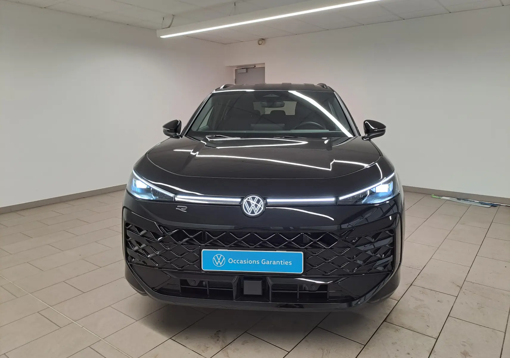Vue frontale du Volkswagen T-Roc 2026 noir ébène avec phares matrix LED allumés et calandre R-Line distinctive.