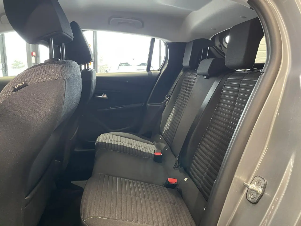 Vue intérieure côté droit sur la banquette arrière noire avec détails de sellerie tissu dans une Peugeot 208 gris clair 2024.