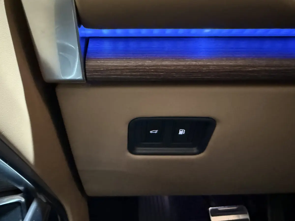 Détail intérieur montrant les boutons d'ouverture du coffre et de la trappe à carburant sur un Range Rover noir.