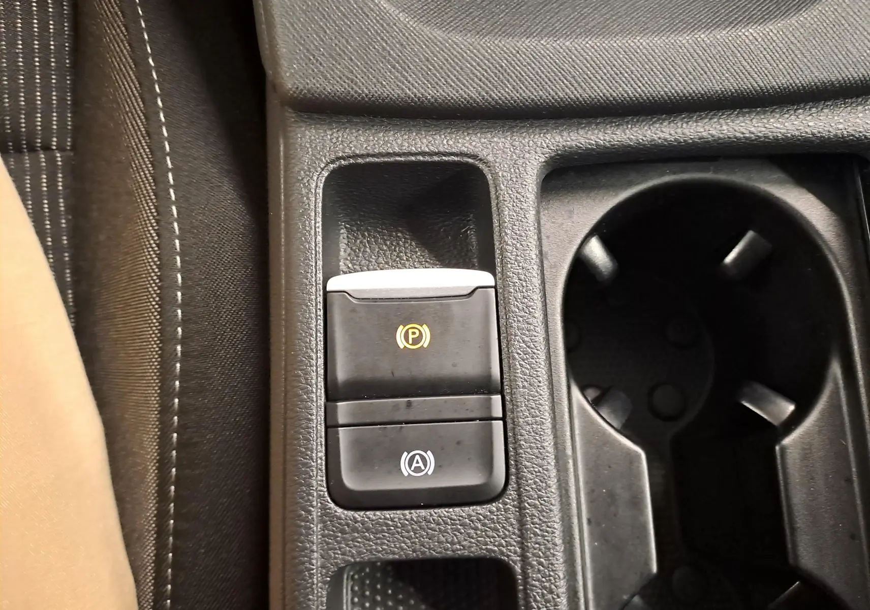 Gros plan sur la console centrale de la Skoda Octavia Combi blanche, montrant les boutons du frein à main électronique et de l'arrêt/start automatique.