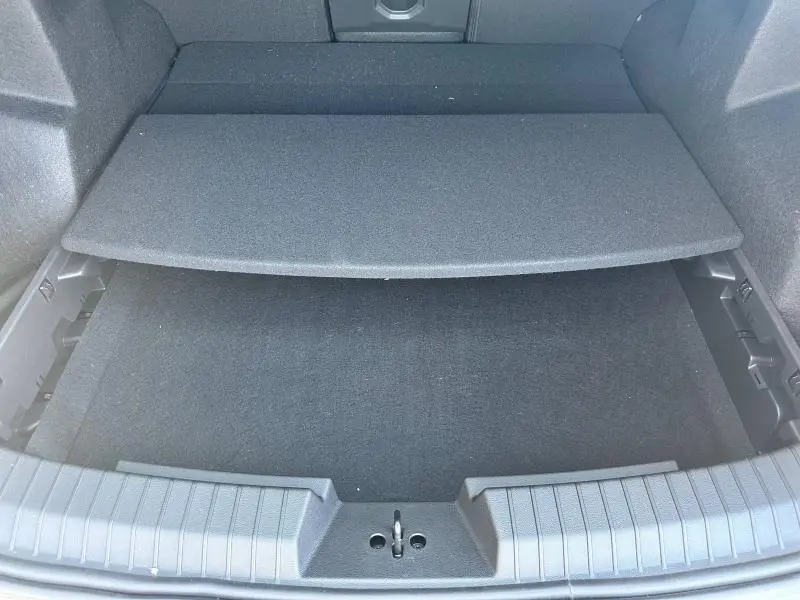 Vue intérieure du coffre du Dacia Bigster 2025 blanc, montrant le double plancher de rangement en tissu noir.