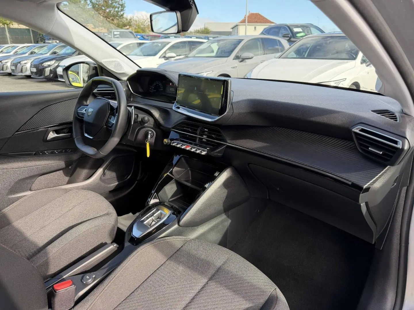 Intérieur avant droit de la Peugeot 208 1.2 Hybrid gris Artense avec tableau de bord moderne et écran tactile central.