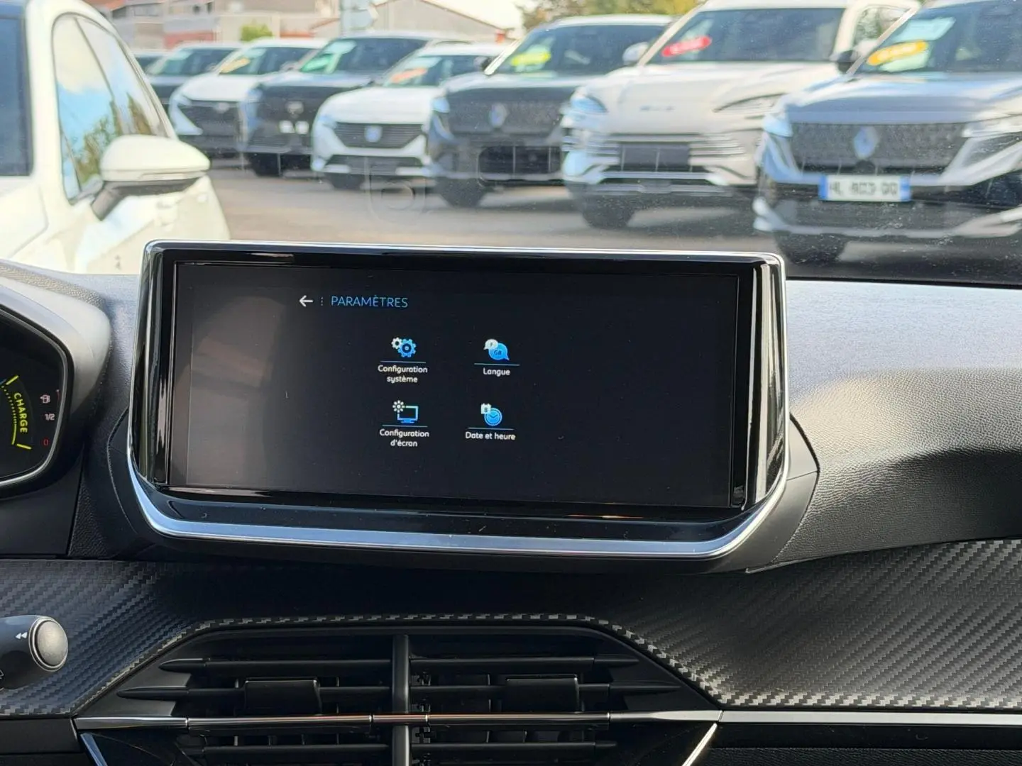Vue intérieure centrée sur l'écran tactile du tableau de bord de la Peugeot 208 gris Artense, avec finition carbone.
