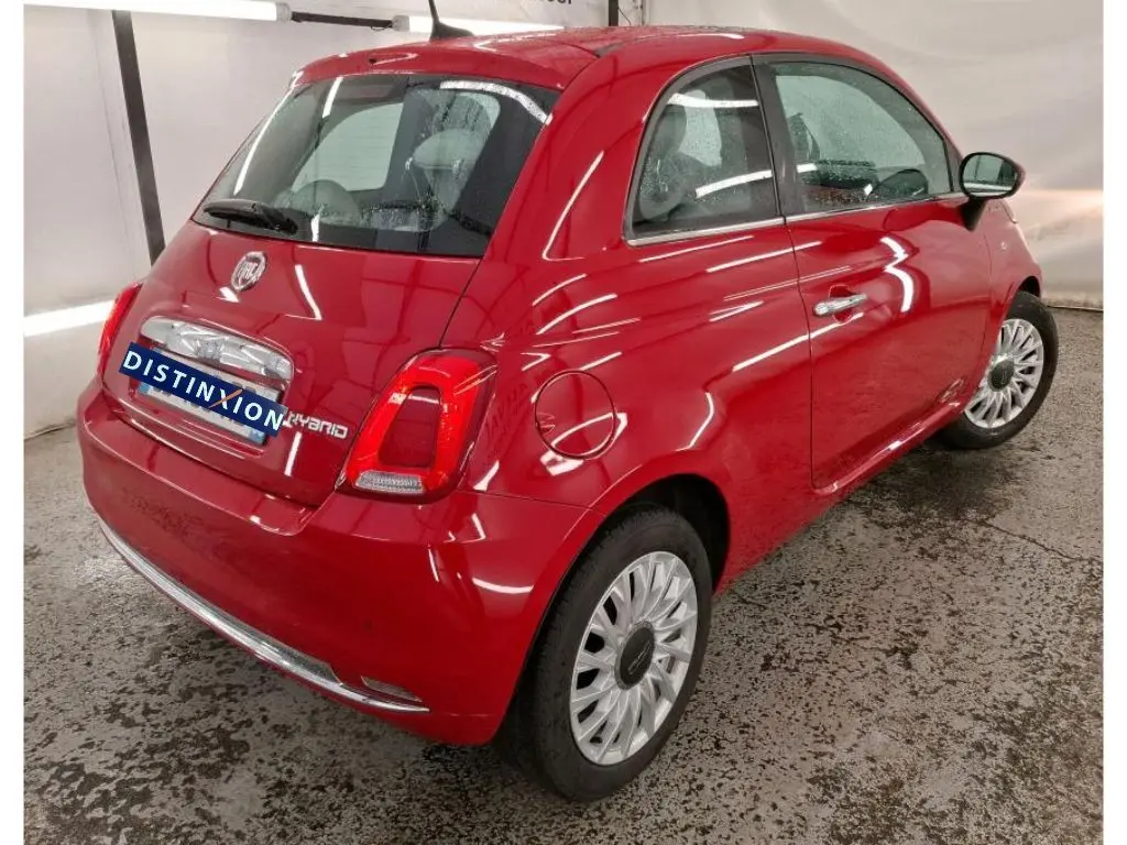 Vue 3/4 arrière droite d'une FIAT 500 Dolcevita rouge avec logo Hybrid et jantes multibranches en intérieur.