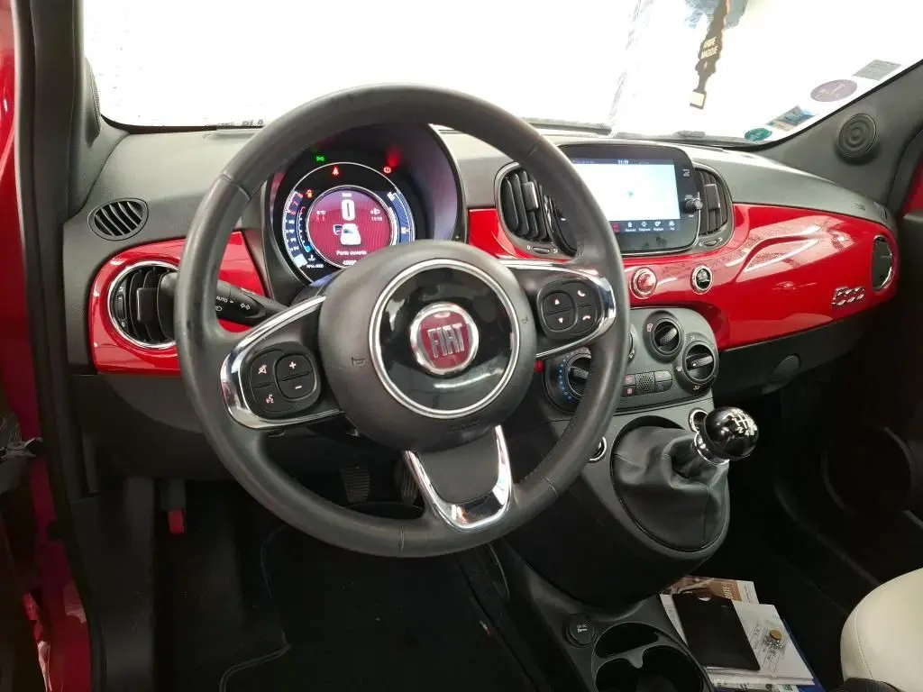 Vue intérieure avant de la FIAT 500 Dolcevita rouge, volant multifonction et tableau de bord brillant avec écran tactile.