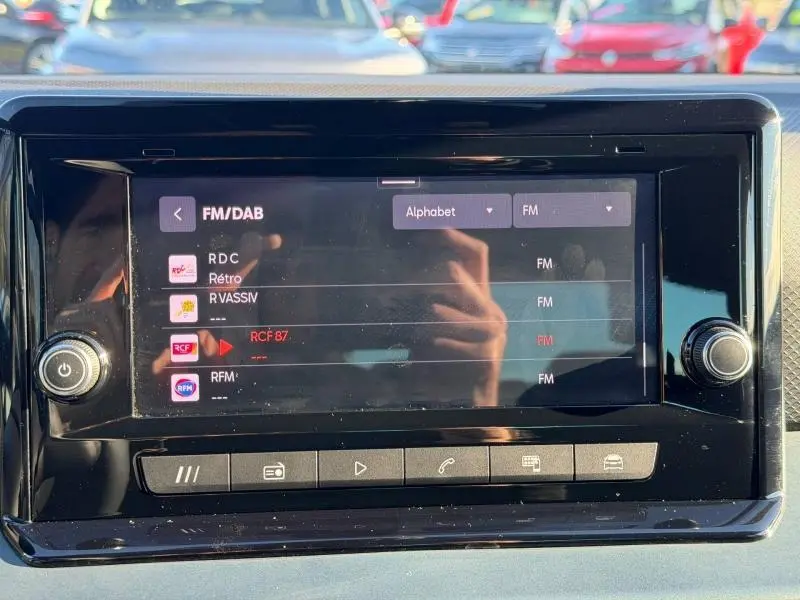 Écran tactile central du SEAT Arona 2025 affichant les stations FM/DAB, vue frontale en intérieur noir brillant.