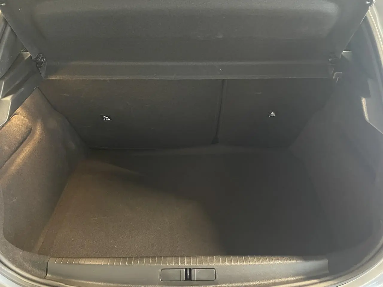 Coffre ouvert de la Peugeot 208 gris clair, vue intérieure montrant l'espace de rangement vide.