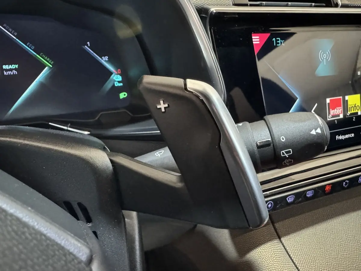 Gros plan sur la palette de changement de vitesse droite et l'écran tactile du tableau de bord du DS7 Crossback E-TENSE gris foncé.