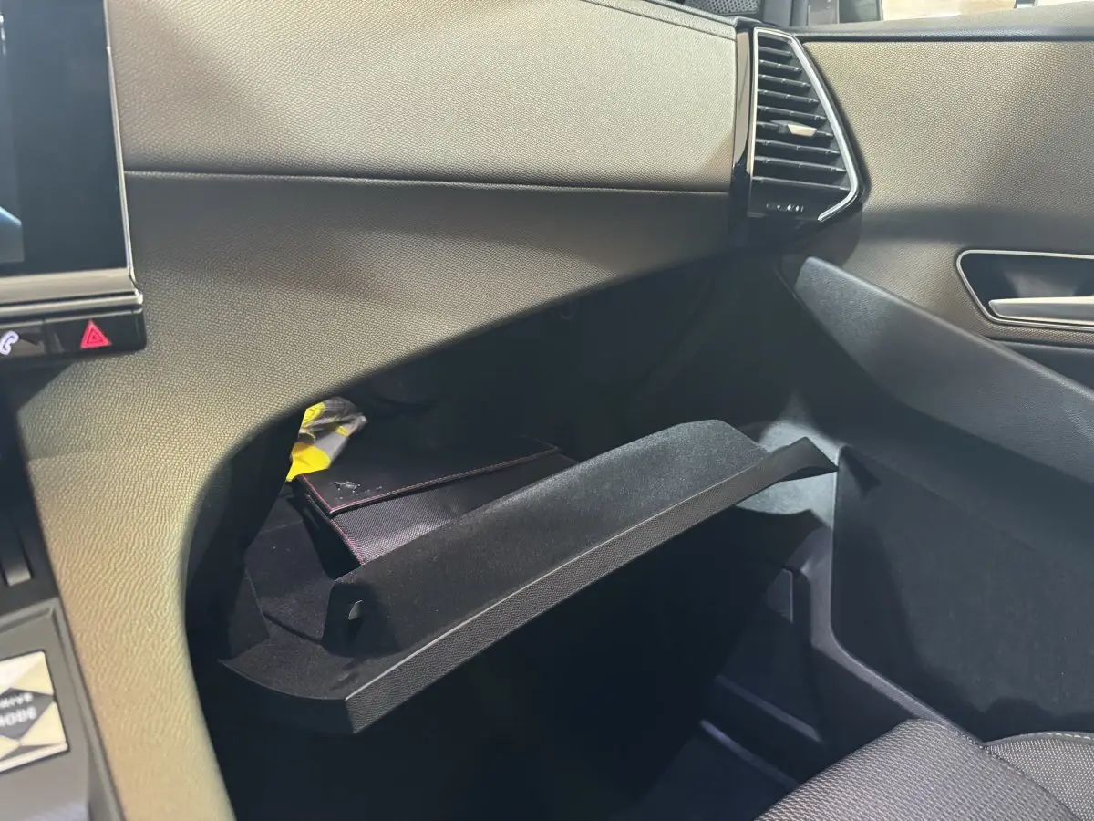 Vue intérieure côté passager du coffre à gants ouvert du DS7 Crossback gris foncé, montrant la texture du tableau de bord.