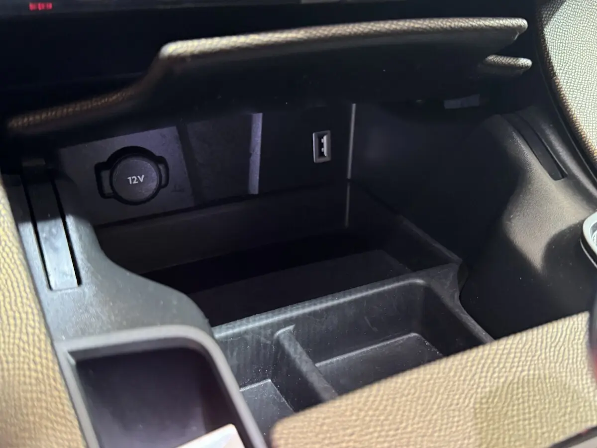 Vue rapprochée de la prise 12V et port USB dans le rangement central intérieur du DS7 Crossback gris foncé.